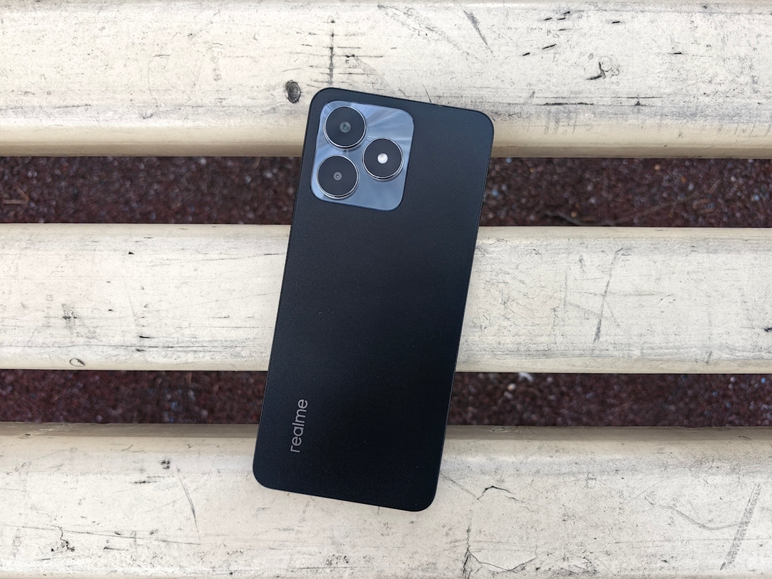 A black smartphone rests on a weathered wooden bench.