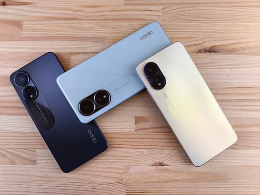 Three smartphones in different colors on a wooden surface
