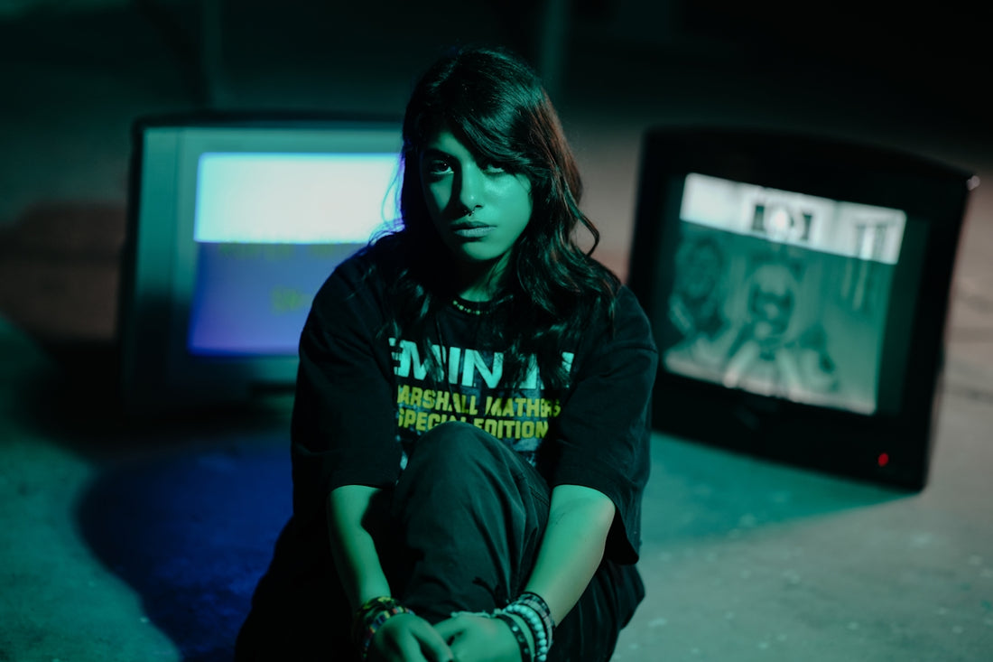 Woman sits between two old televisions