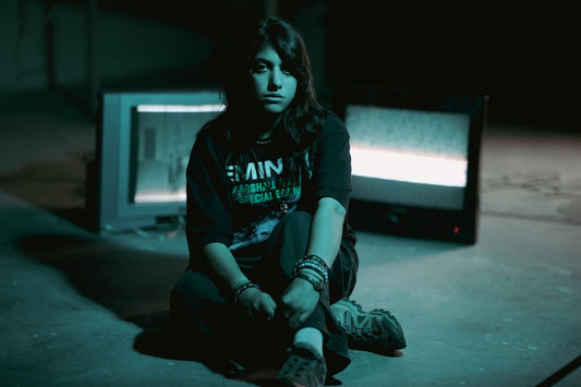 Young woman sits between two old televisions