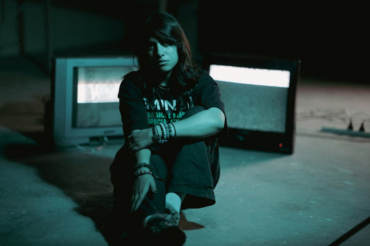 A person sits between two old televisions.