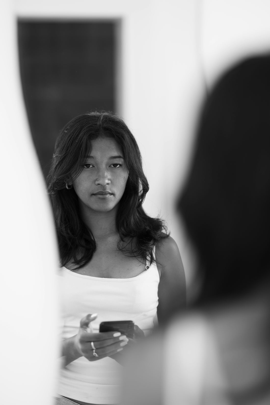 Young woman looking into a mirror holding phone