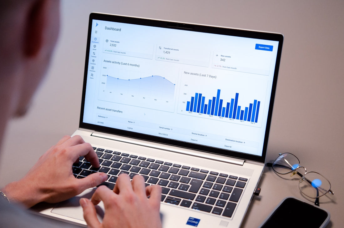 Person typing on laptop with data charts on screen