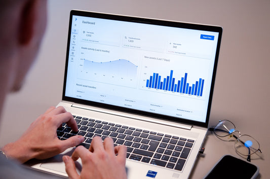 Person typing on laptop with data charts on screen