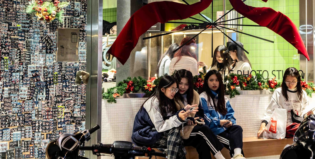 Young women looking at phones near a storefront display